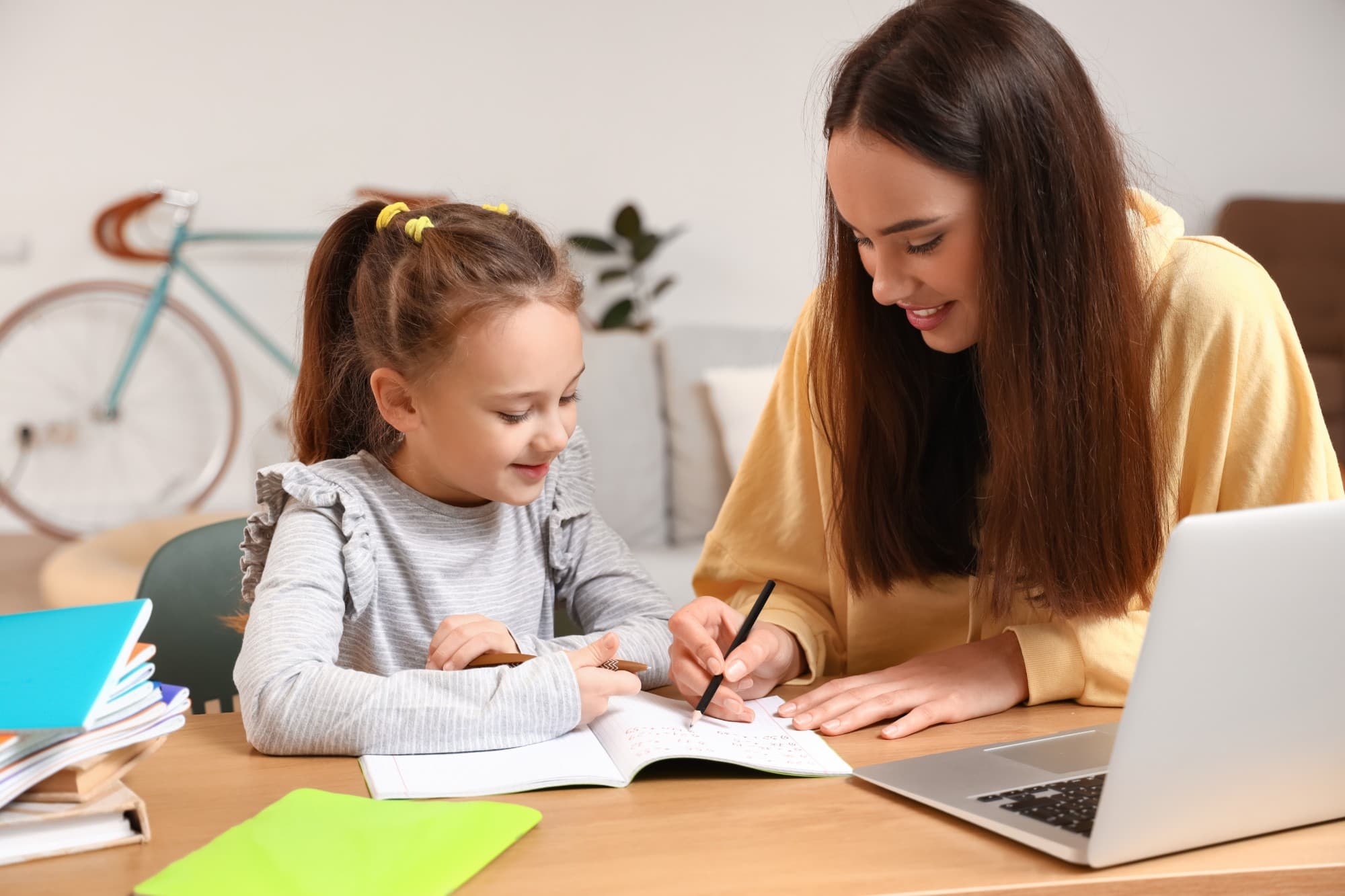 A tutor and a young student smiling over a workbook during a lesson